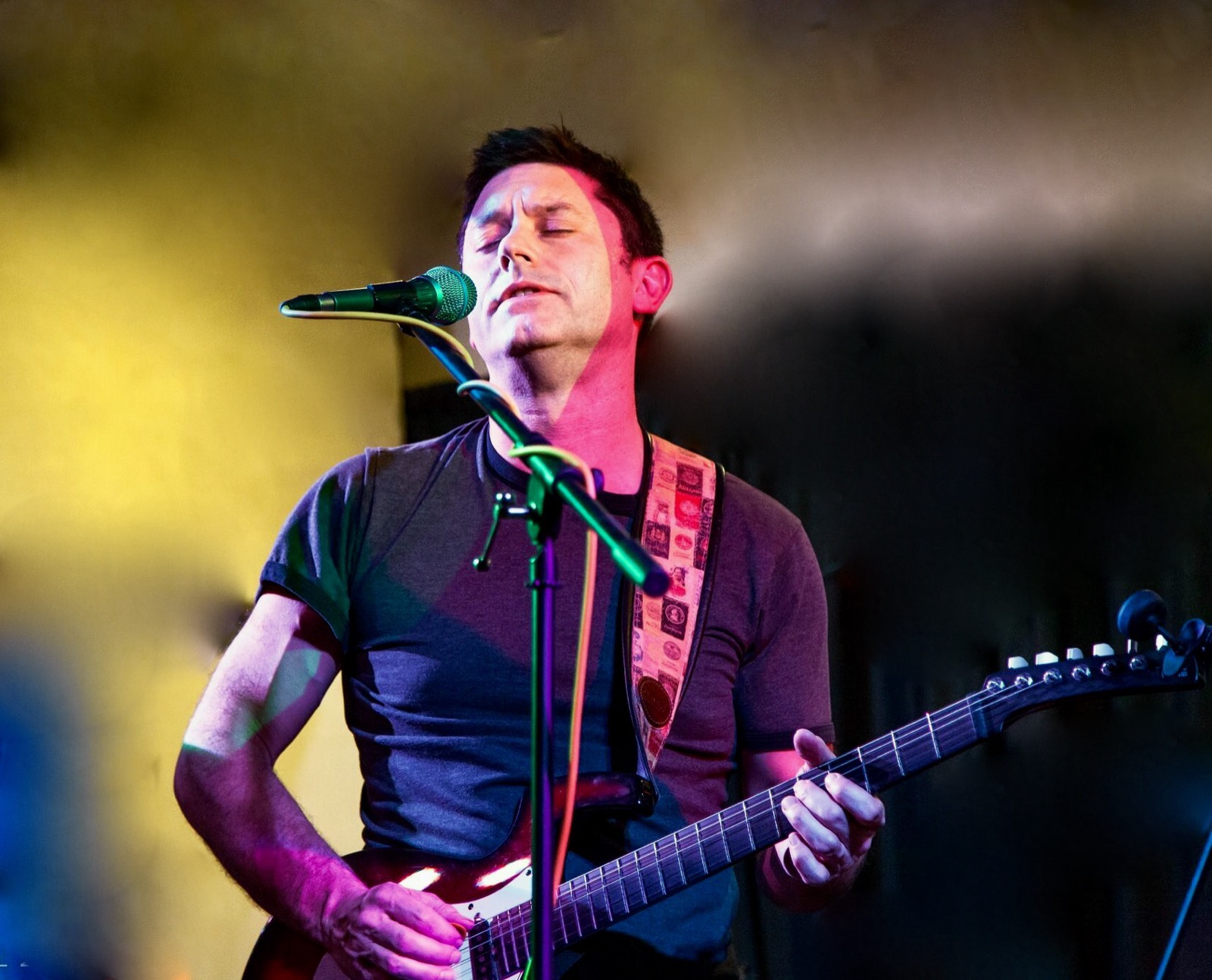 Conor singing and playing guitar under stage lights