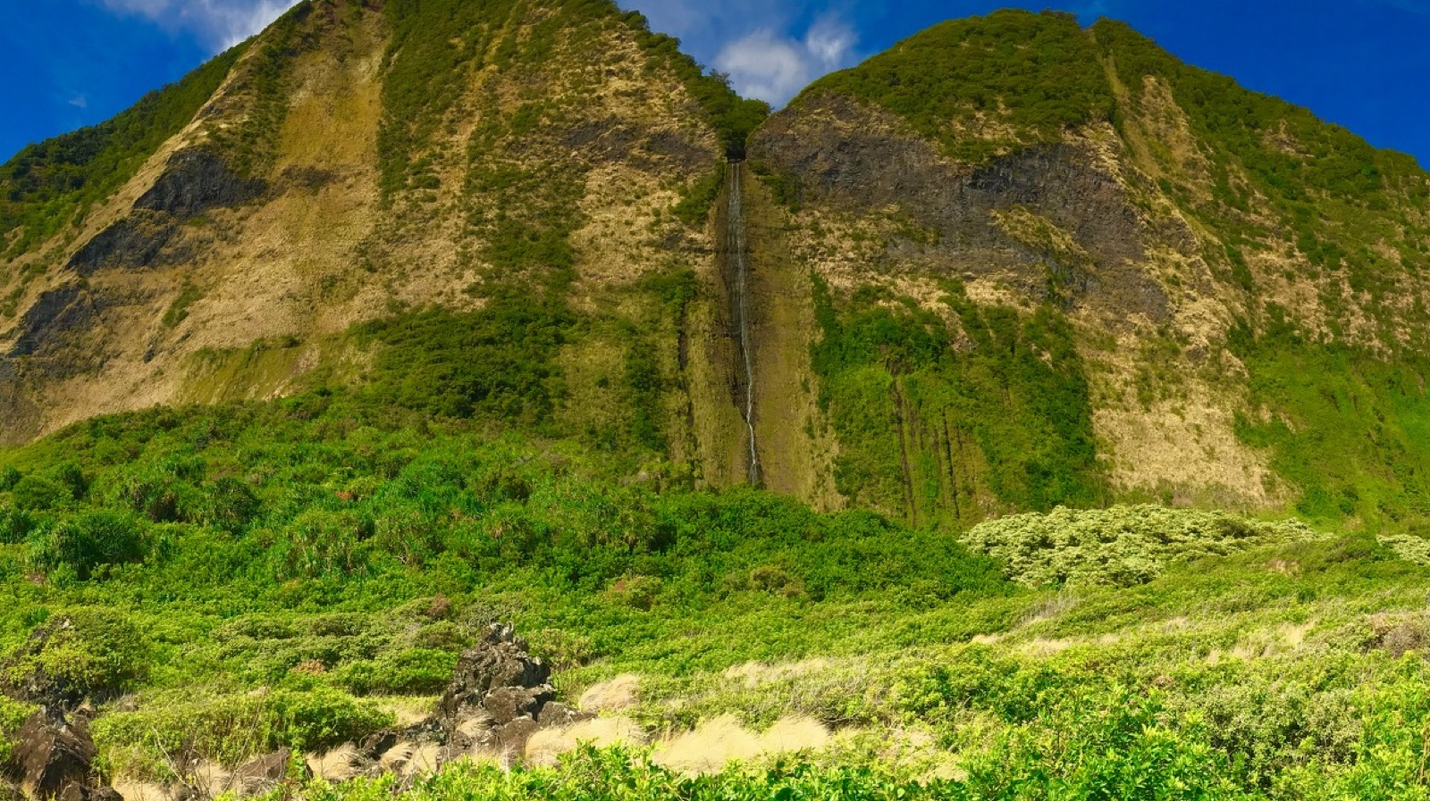 A waterfall streaking down towering green cliffs