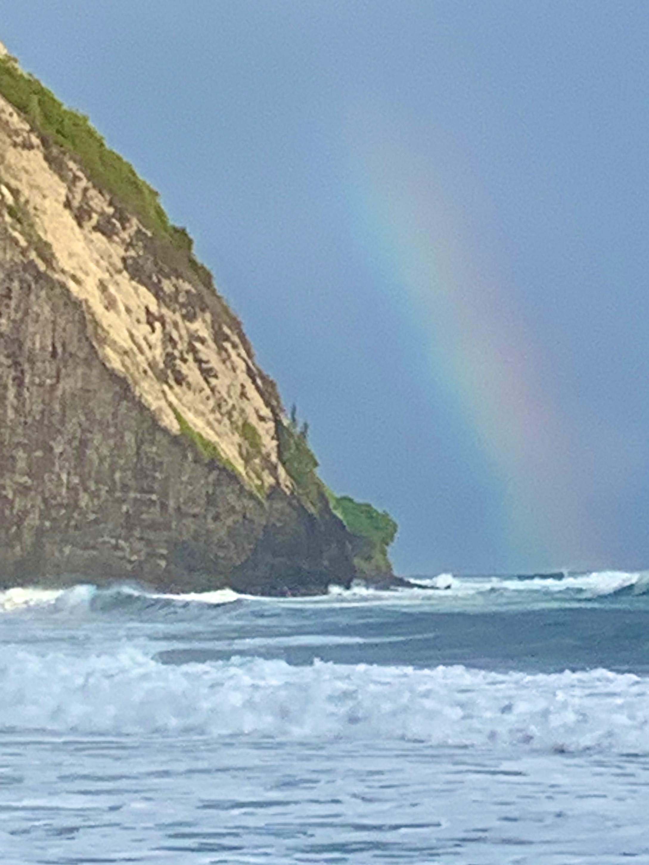 A rainbow arcing beside a sea cliff