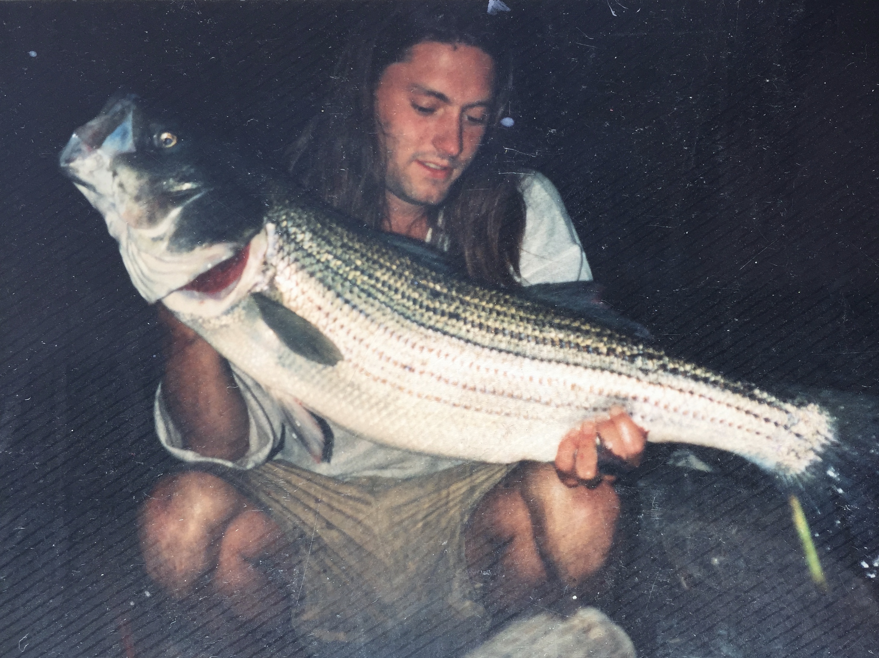A man holding a freshly caught striped bass