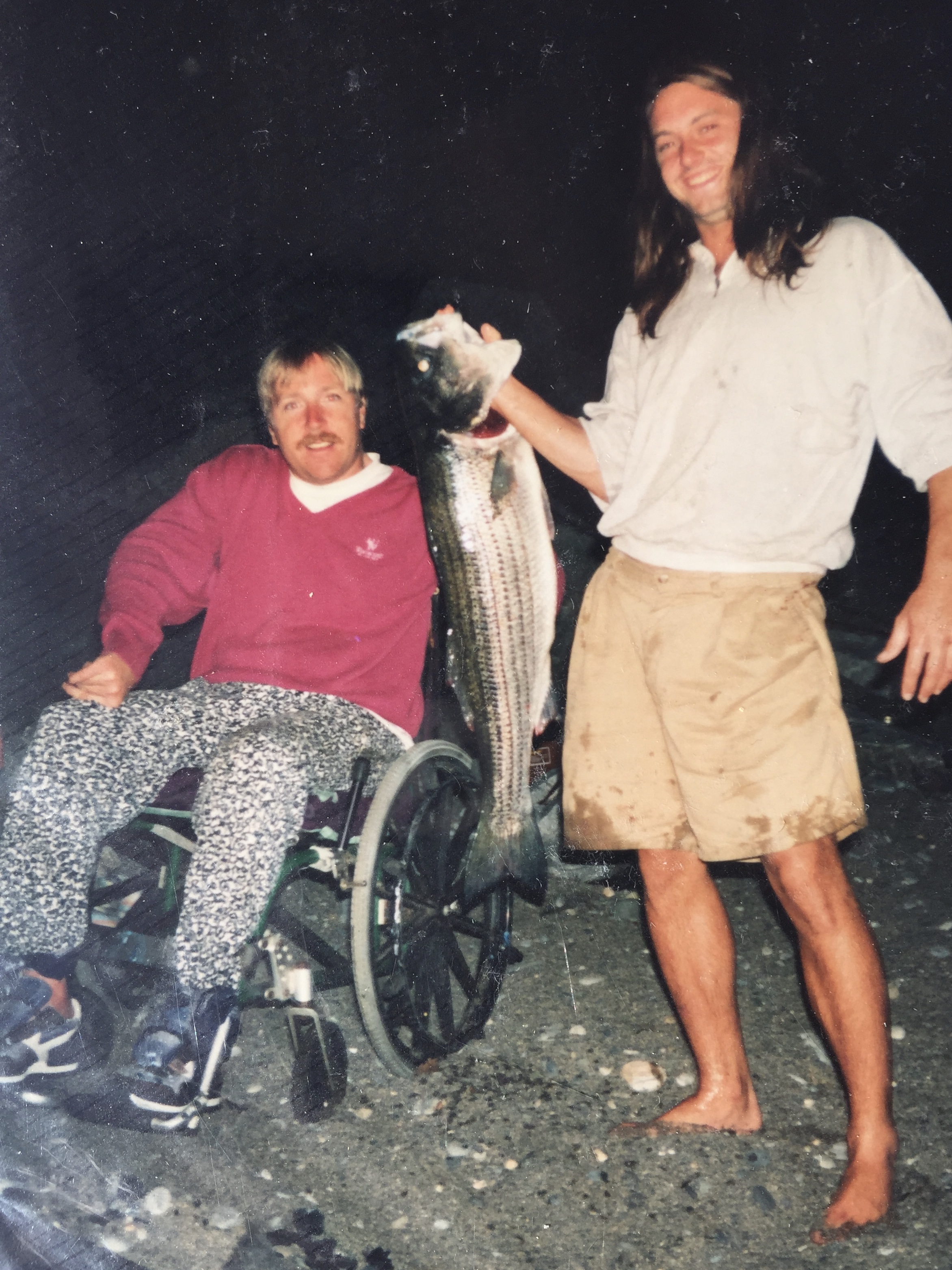 Two men with a freshly caught striped bass